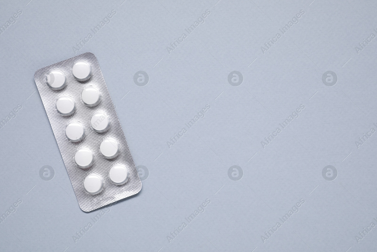 Photo of Antibiotic pills in blister on gray background, top view. Space for text