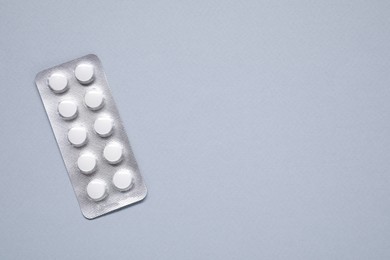 Antibiotic pills in blister on gray background, top view. Space for text