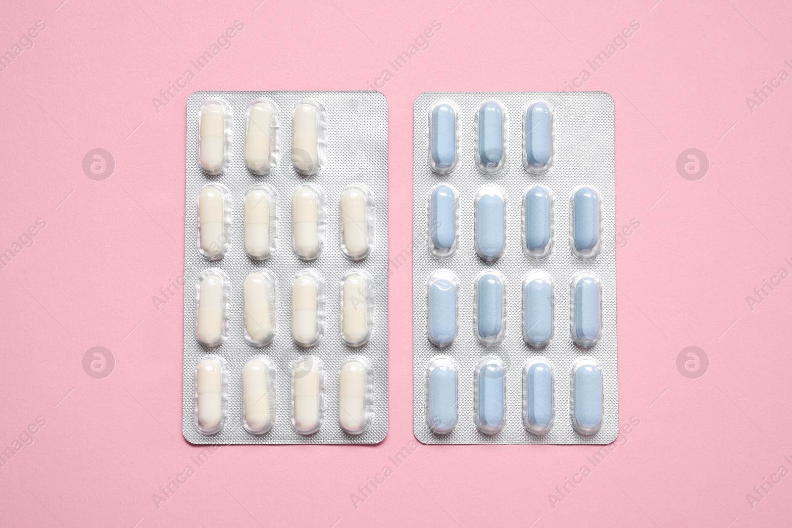 Photo of Antibiotic pills in blisters on pink background, flat lay