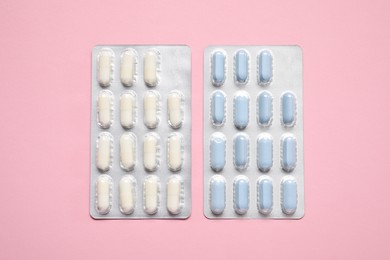 Antibiotic pills in blisters on pink background, flat lay