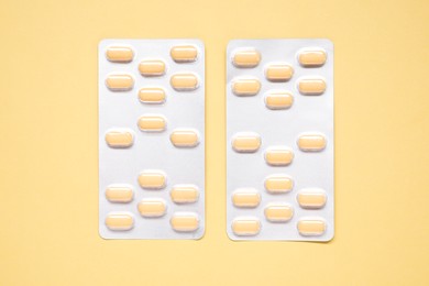 Photo of Antibiotic pills in blisters on yellow background, top view