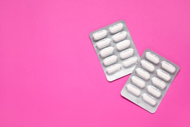 Photo of Antibiotic pills in blisters on pink background, top view. Space for text