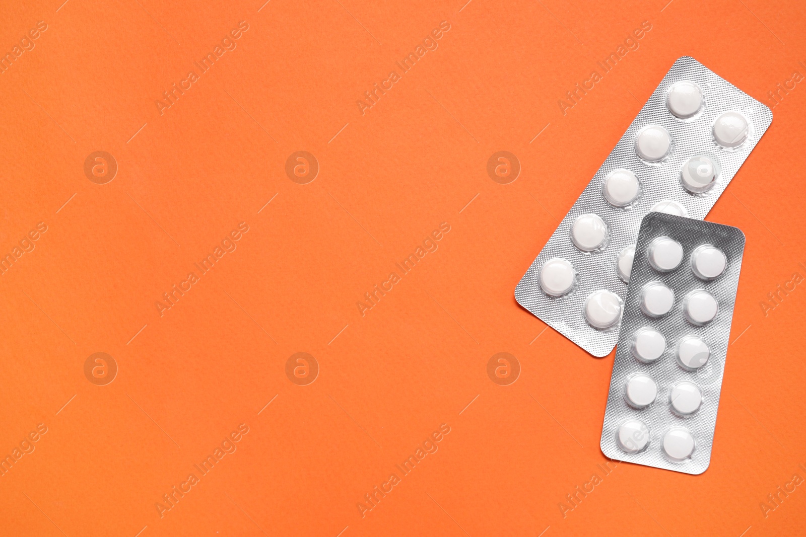 Photo of Antibiotic pills in blisters on orange background, top view. Space for text