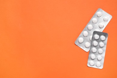 Photo of Antibiotic pills in blisters on orange background, top view. Space for text