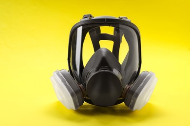 One full face respirator on yellow background, closeup