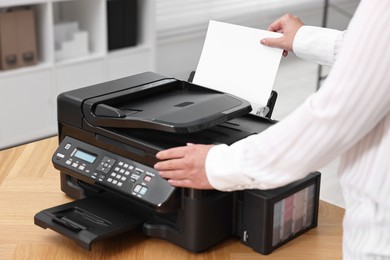 Photo of Woman using modern printer at workplace indoors, closeup