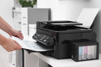 Photo of Woman using modern printer at workplace indoors, closeup