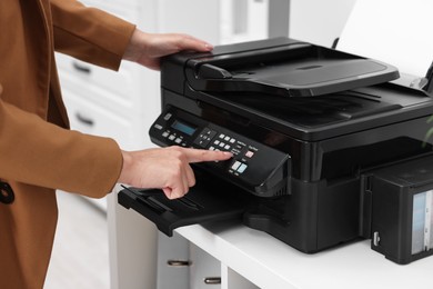 Woman using modern printer at workplace indoors, closeup