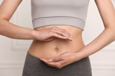 Healthy digestion. Woman holding something near her belly indoors, closeup