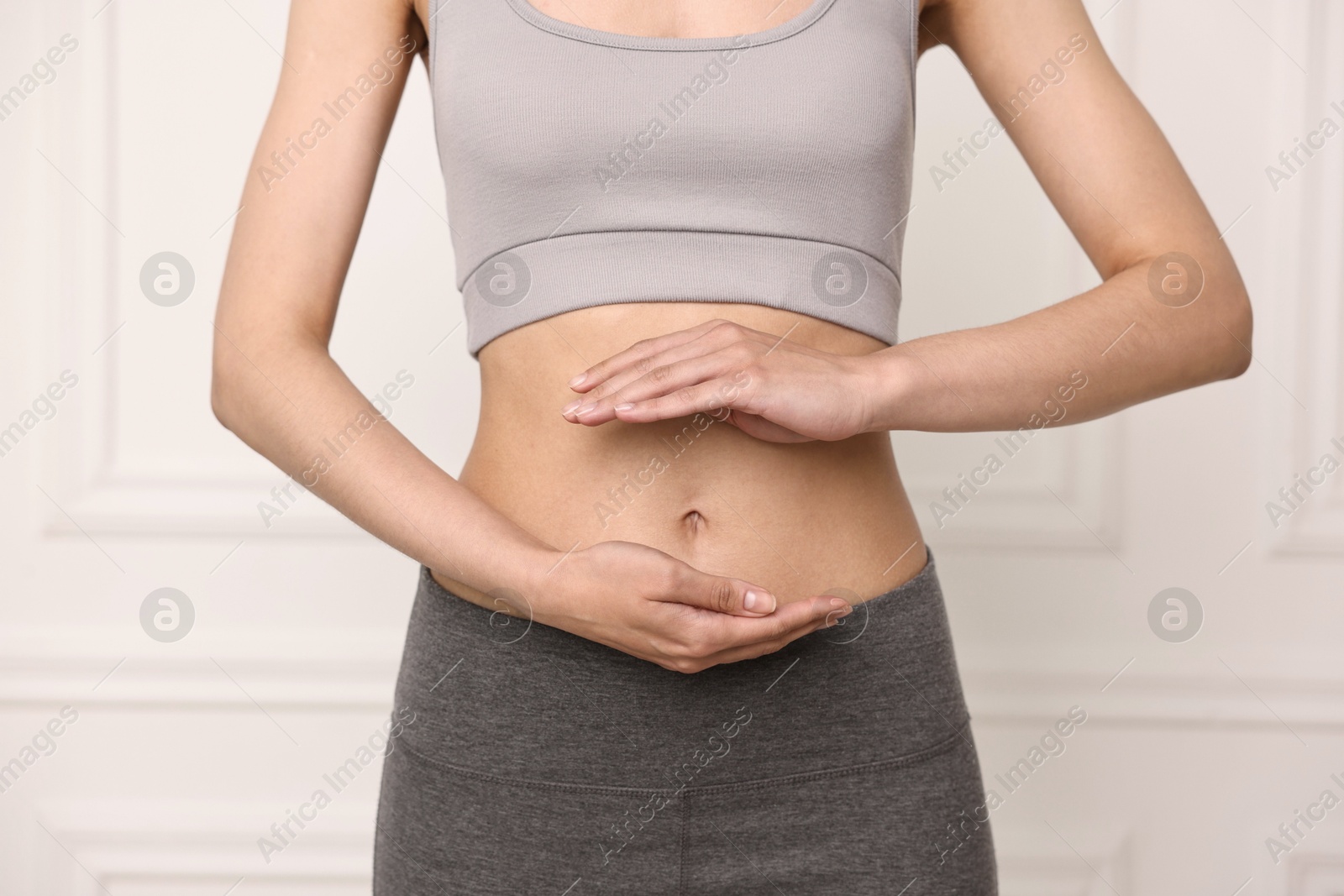 Photo of Healthy digestion. Woman holding something near her belly indoors, closeup