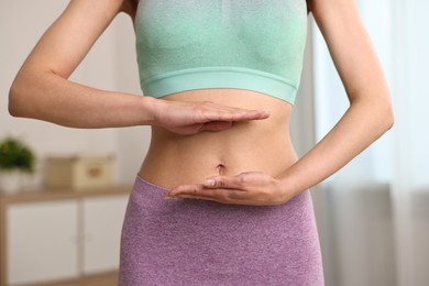 Healthy digestion. Woman holding something near her belly indoors, closeup