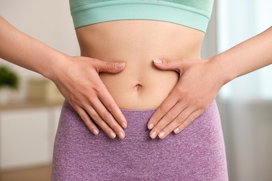 Healthy digestion. Woman touching her belly indoors, closeup