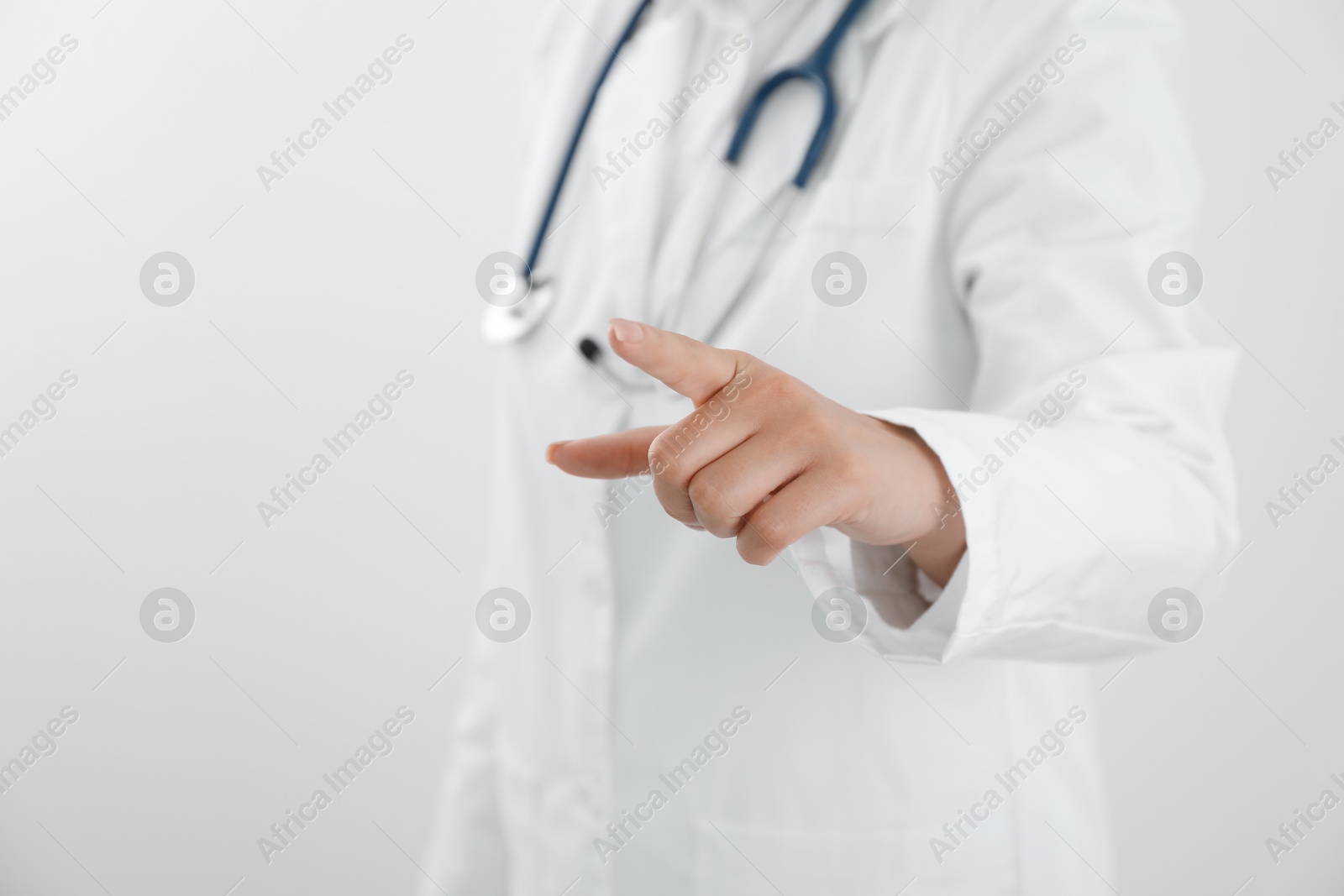 Photo of Doctor pointing at something on white background, closeup. Space for text