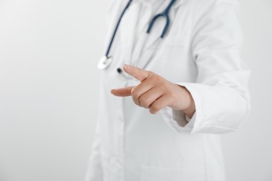 Photo of Doctor pointing at something on white background, closeup. Space for text