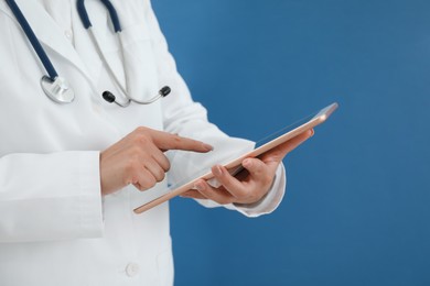 Photo of Doctor with tablet on blue background, closeup view