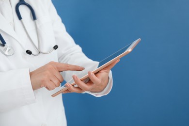 Doctor with tablet on blue background, closeup view