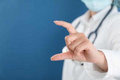 Photo of Doctor holding something on blue background, closeup. Space for text