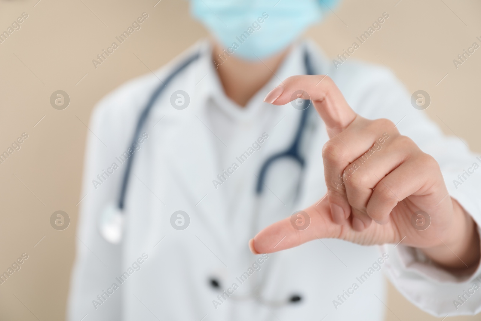 Photo of Doctor holding something on beige background, closeup