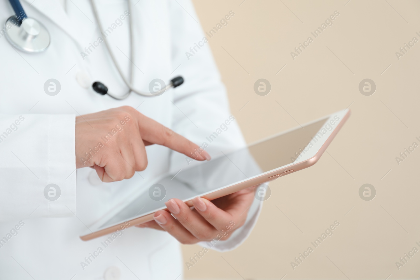 Photo of Doctor with tablet on beige background, closeup view