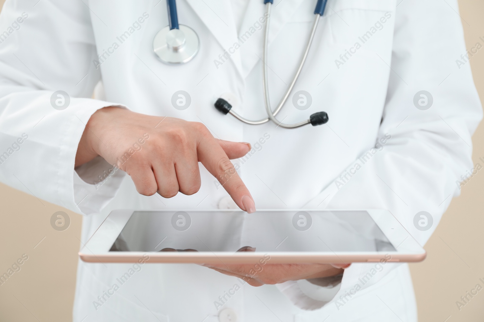 Photo of Doctor with tablet on beige background, closeup view