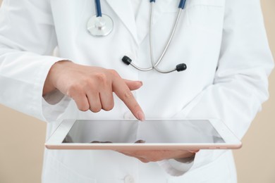 Photo of Doctor with tablet on beige background, closeup view