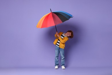 Photo of Little boy with rainbow umbrella on purple background