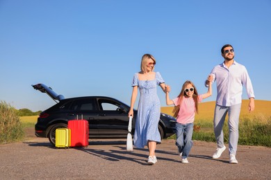 Parents, their daughter, car and suitcases outdoors. Family traveling