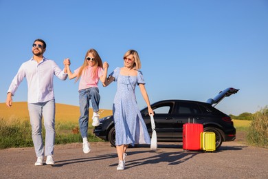 Parents, their daughter, car and suitcases outdoors. Family traveling