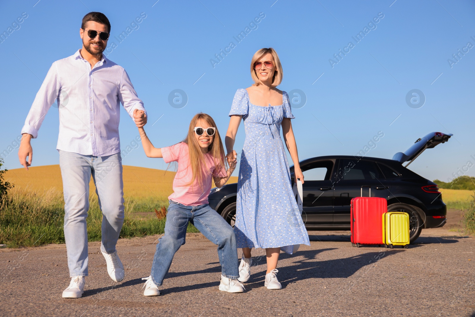 Photo of Parents, their daughter, car and suitcases outdoors. Family traveling