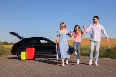 Parents, their daughter, car and suitcases outdoors. Family traveling