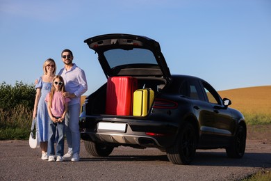 Happy family near car with suitcases outdoors