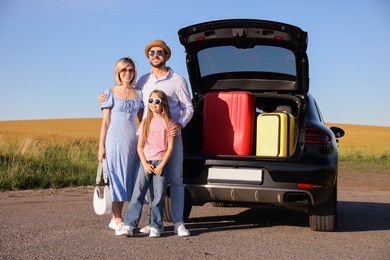 Happy family near car with suitcases outdoors