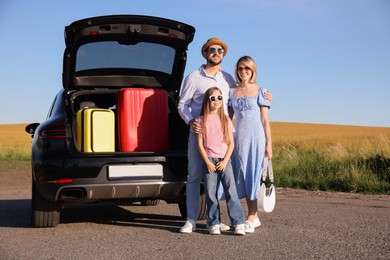 Happy family near car with suitcases outdoors