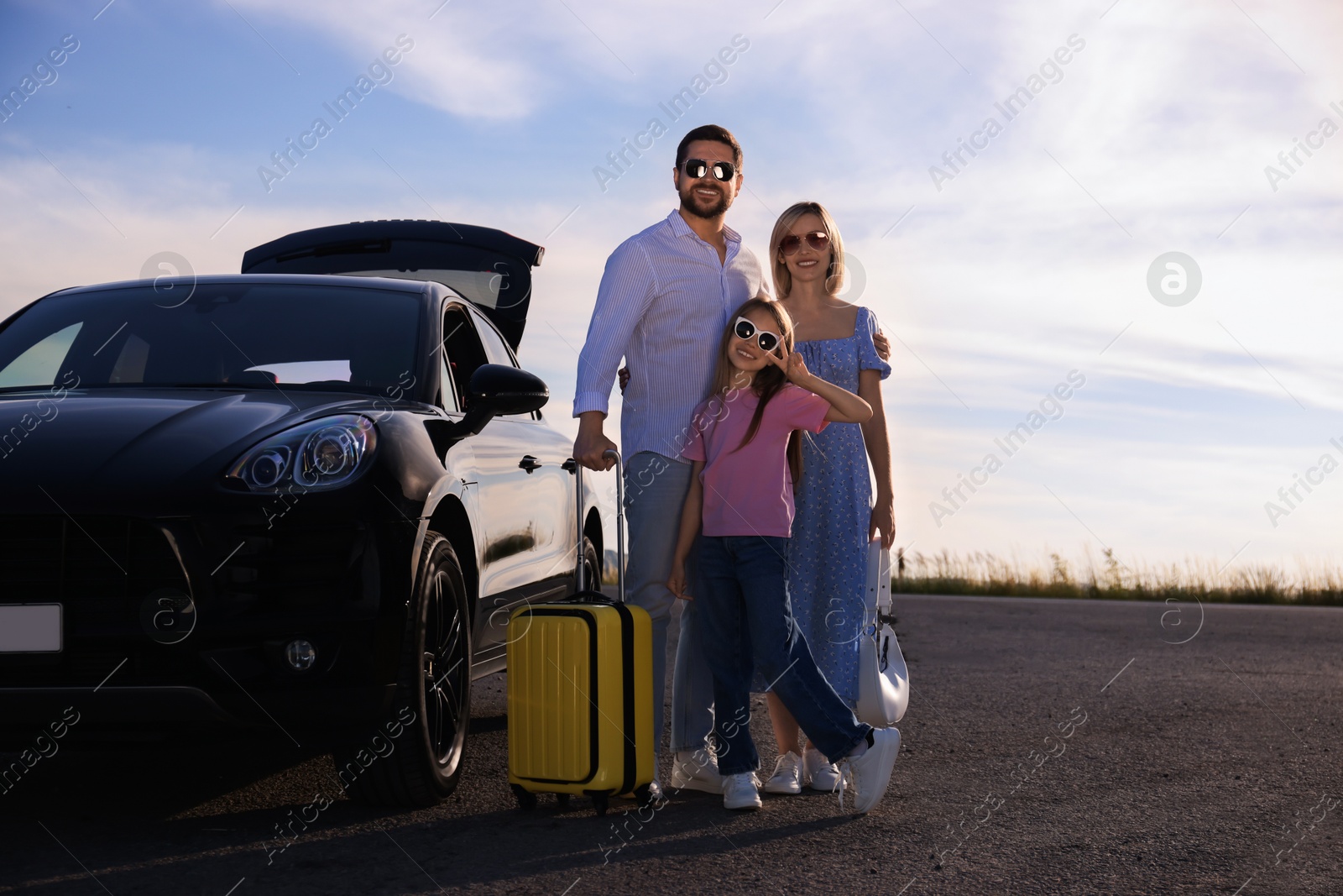 Photo of Happy family with suitcase near car outdoors, space for text