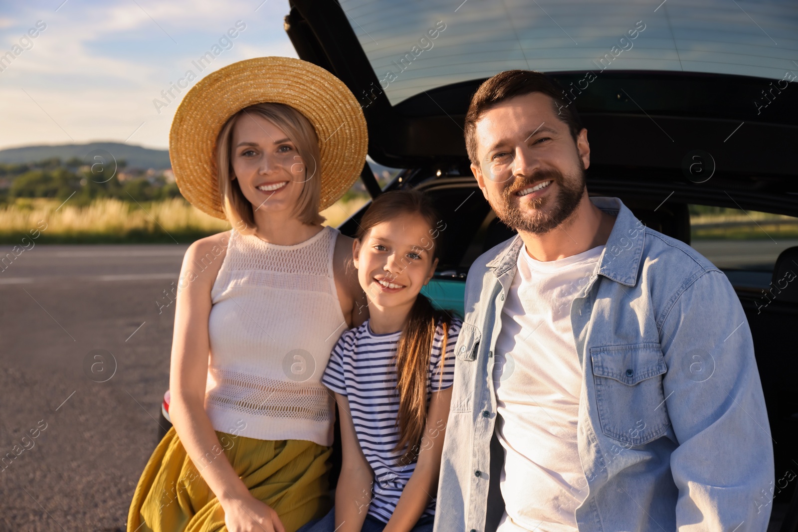 Photo of Happy family sitting in trunk of car outdoors