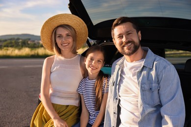 Photo of Happy family sitting in trunk of car outdoors