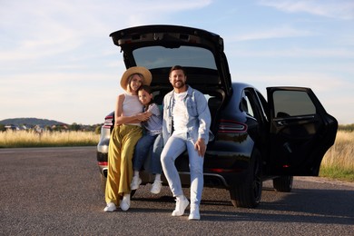 Happy family sitting in trunk of car outdoors