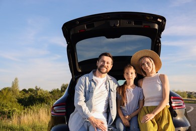 Happy family sitting in trunk of car outdoors