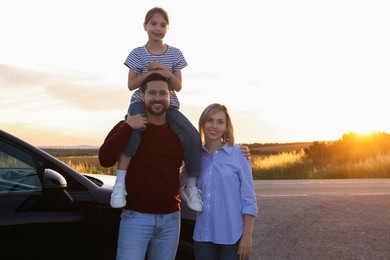 Happy parents and their daughter near car outdoors, space for text