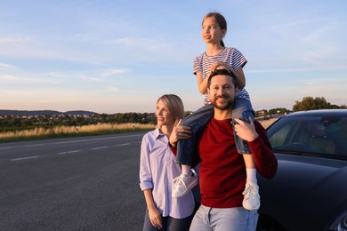 Photo of Happy parents and their daughter near car outdoors, space for text