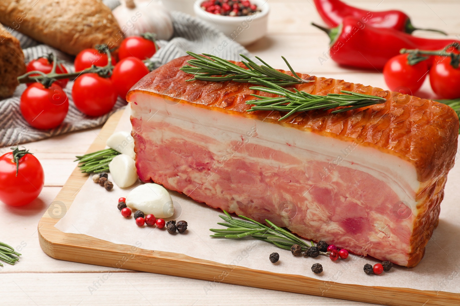 Photo of Piece of raw bacon with spices and cherry tomatoes on white wooden table