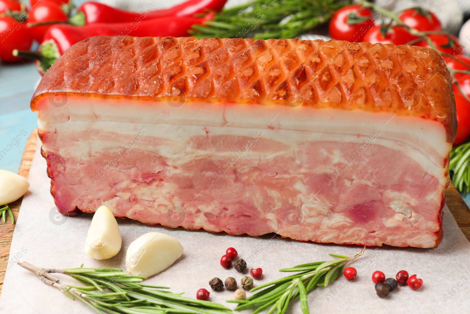 Photo of Piece of raw bacon with spices and cherry tomatoes on light blue table, closeup