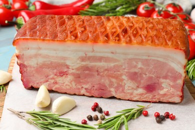 Photo of Piece of raw bacon with spices and cherry tomatoes on light blue table, closeup