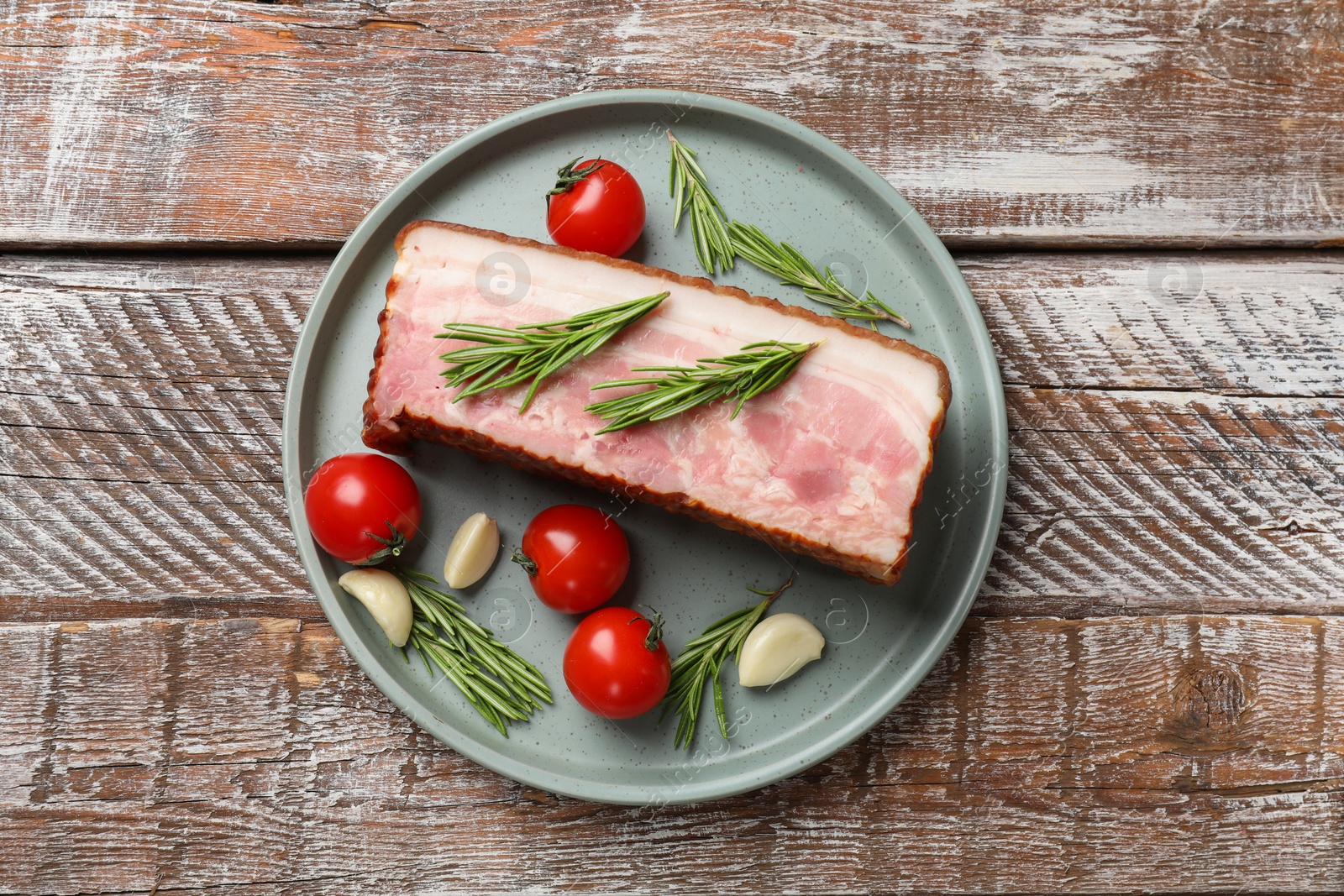 Photo of Piece of raw bacon with spices and cherry tomatoes on wooden table, top view