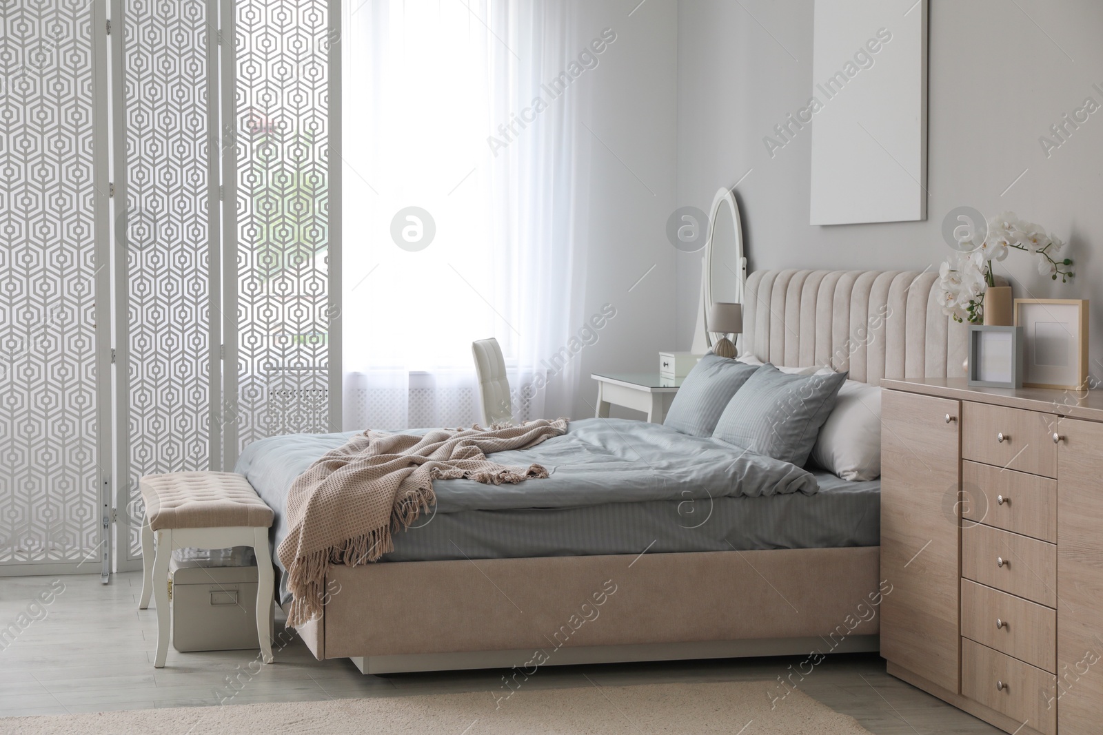 Photo of Folding screen, mirror and comfortable bed in bedroom. Interior design