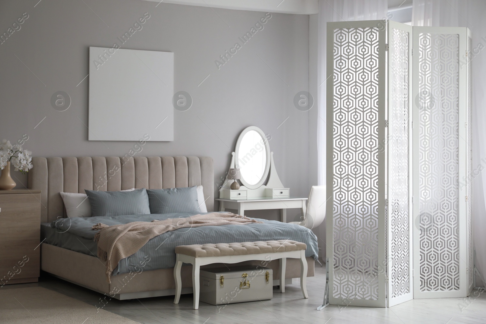 Photo of Folding screen, mirror and comfortable bed in bedroom. Interior design