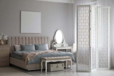 Folding screen, mirror and comfortable bed in bedroom. Interior design