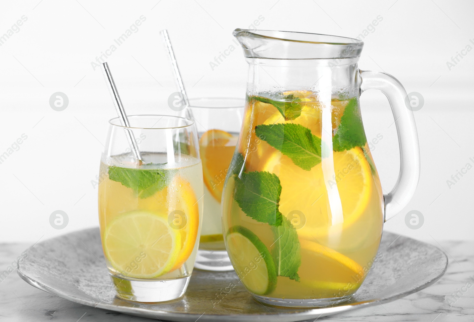 Photo of Freshly made lemonade with mint in jug and glasses on white marble table