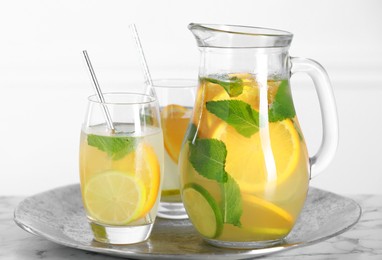 Photo of Freshly made lemonade with mint in jug and glasses on white marble table