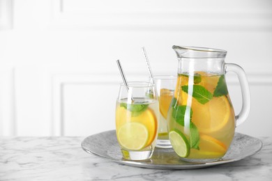 Photo of Freshly made lemonade with mint in jug and glasses on white marble table